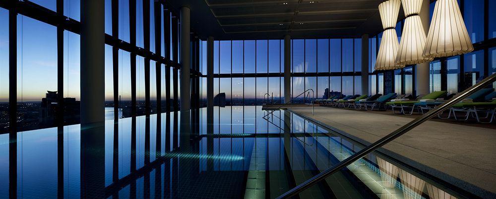 Hotel Crown Metropol Melbourne Esterno foto The photo shows an indoor swimming pool, featuring large floor-to-ceiling windows that provide a stunning view of the skyline at dusk. The lighting creates a serene atmosphere, reflecting both the pool's surface and the darkening sky outside. There a