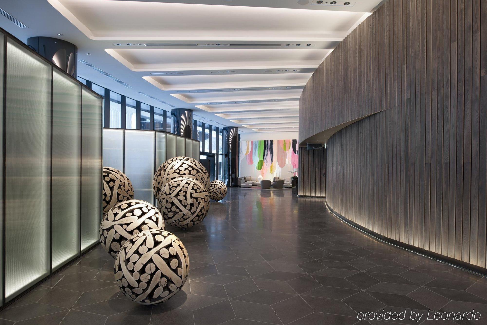 Hotel Crown Metropol Melbourne Esterno foto The image shows a modern interior space, likely a lobby or reception area. The design features a combination of smooth curved walls and sleek surfaces, creating a sophisticated atmosphere. 

In the foreground, there are three large decorative spheres